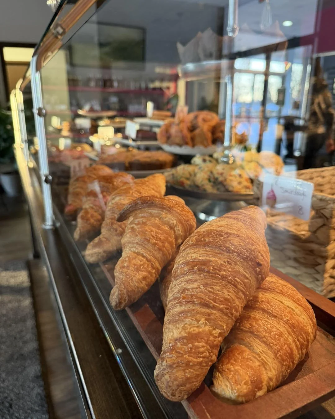 Fresh croissants displayed inside a bakery showcase.