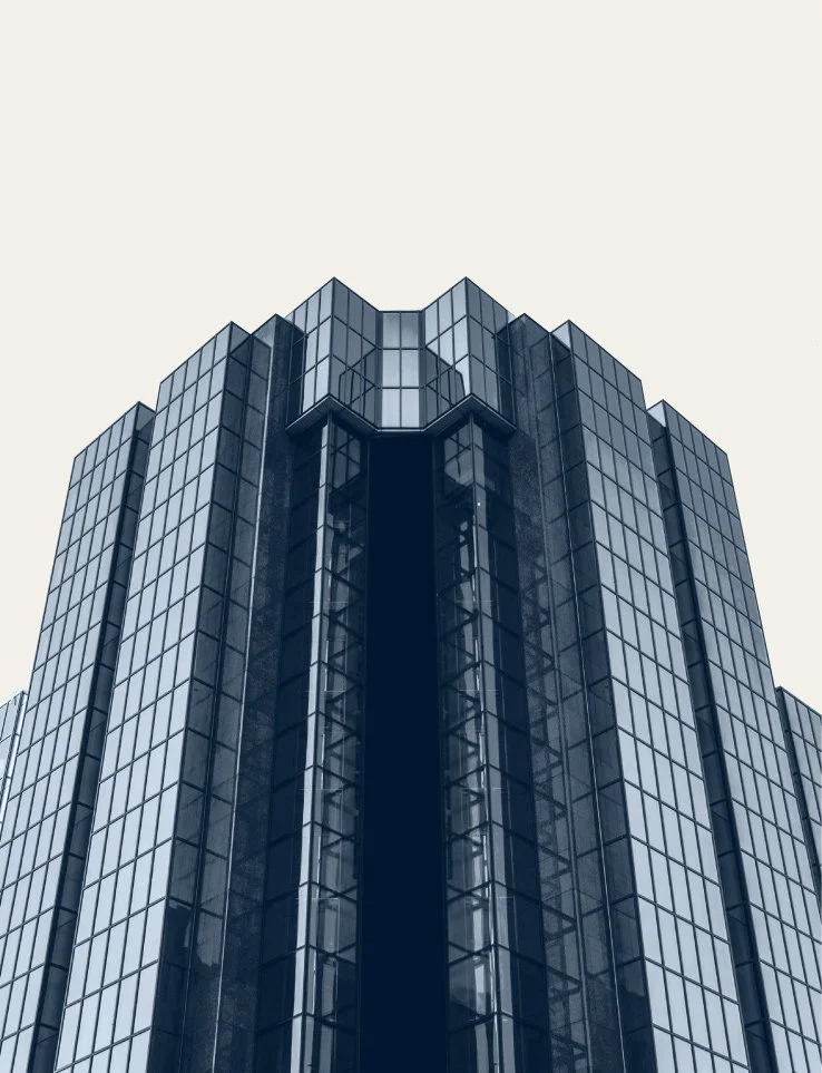 Tall modern glass office building with reflective windows against a light sky.