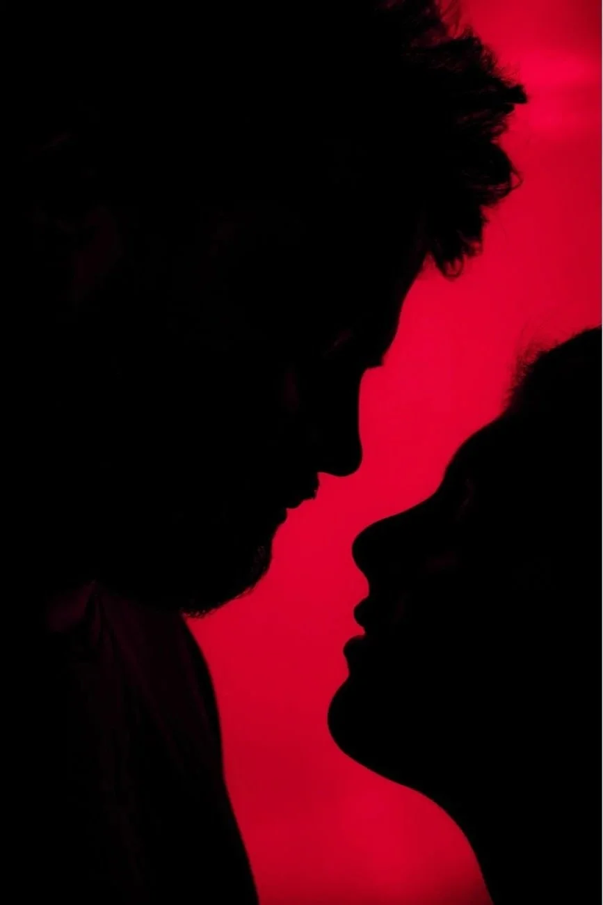 Silhouettes of a man and a woman with their foreheads touching, set against a red background.