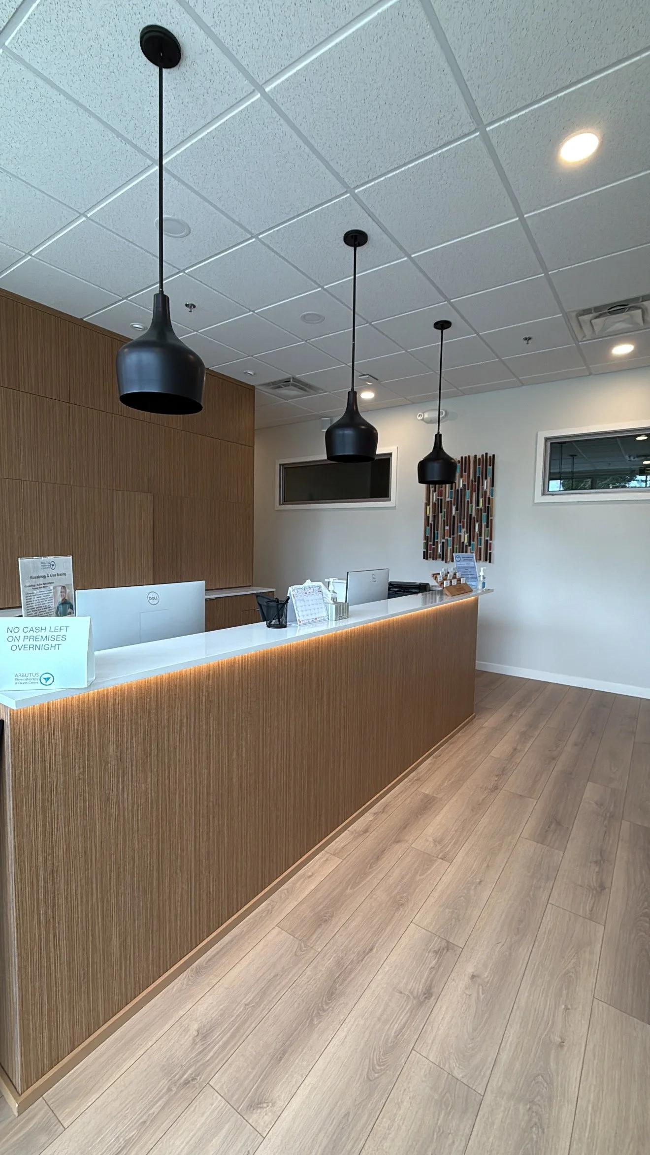 Reception desk in a modern office or clinic with black pendant lights and wood paneling.