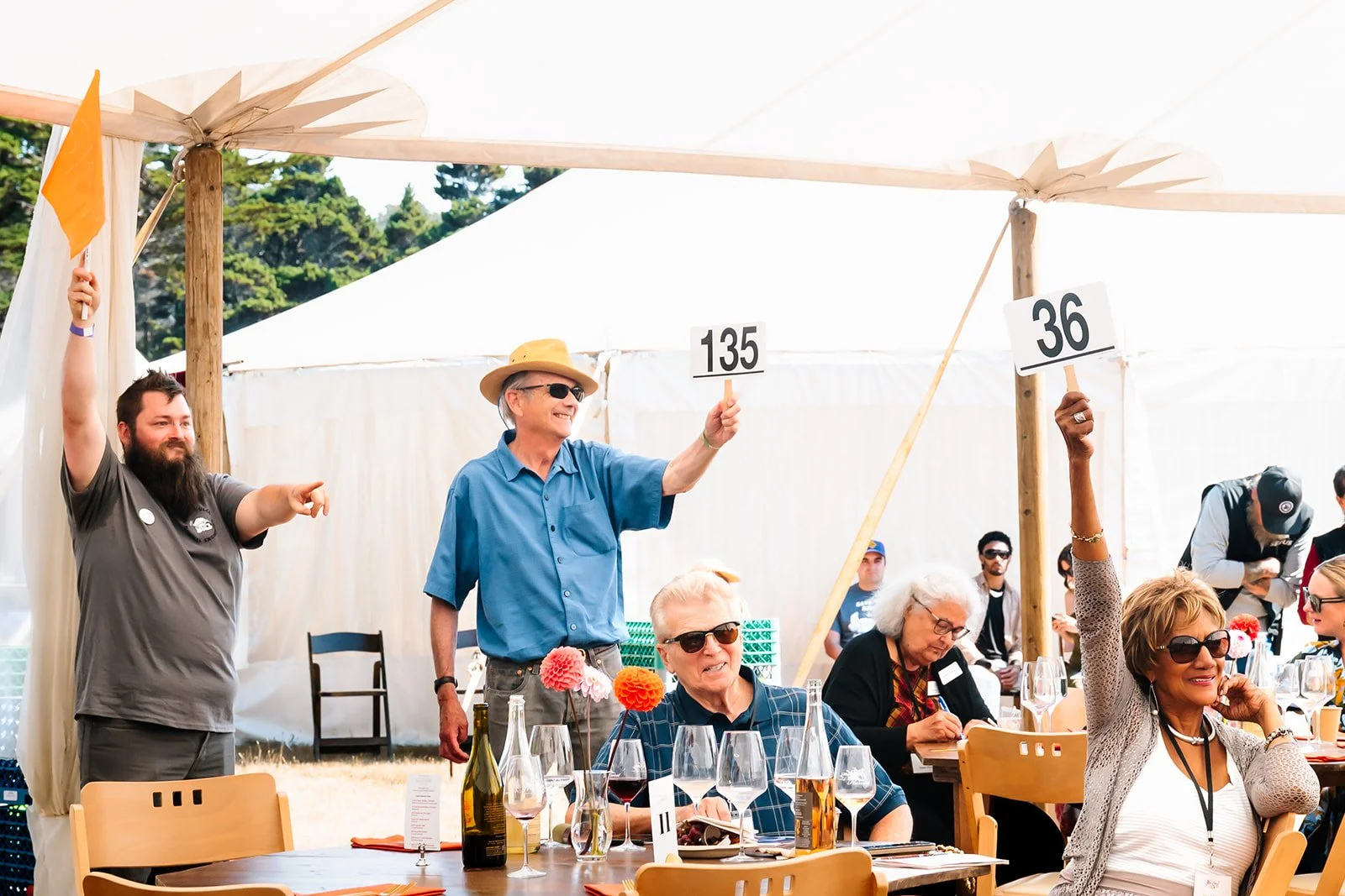 Winesong Live Auction, auction bidder holding up panel 135 in crowd