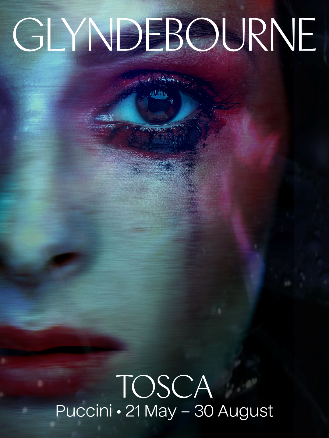 Close-up of a woman's face with bold makeup, featuring a vivid eye look, pink eyeshadow, and red lips, promoting a Tosca opera performance at Glyndebourne from May 21 to August 30, with the name Puccini.