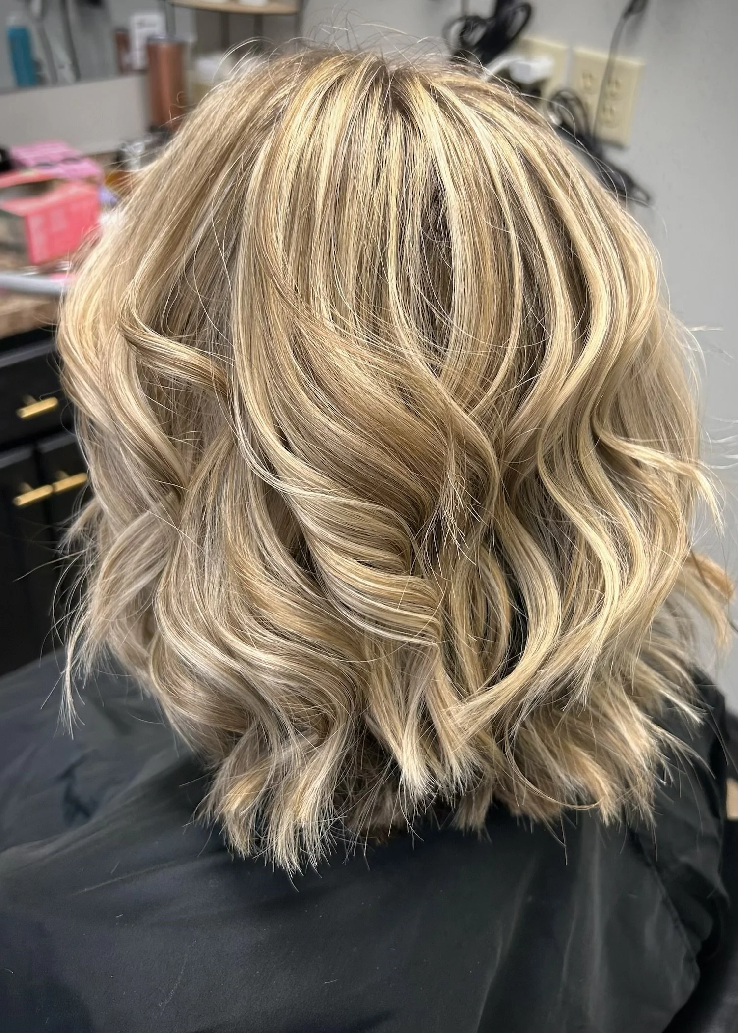 Blonde, wavy, curled hair with highlights styled in loose curls.