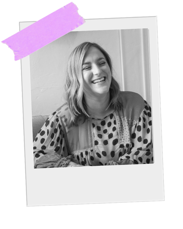 Black and white photo of Emily Carroll Negi, LMFT sitting inside her Nashville therapist office, laughing, wearing a patterned top with polka dots and geometric shapes.