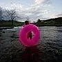 cover design, large hot pink donut held by person, dark landscape in background