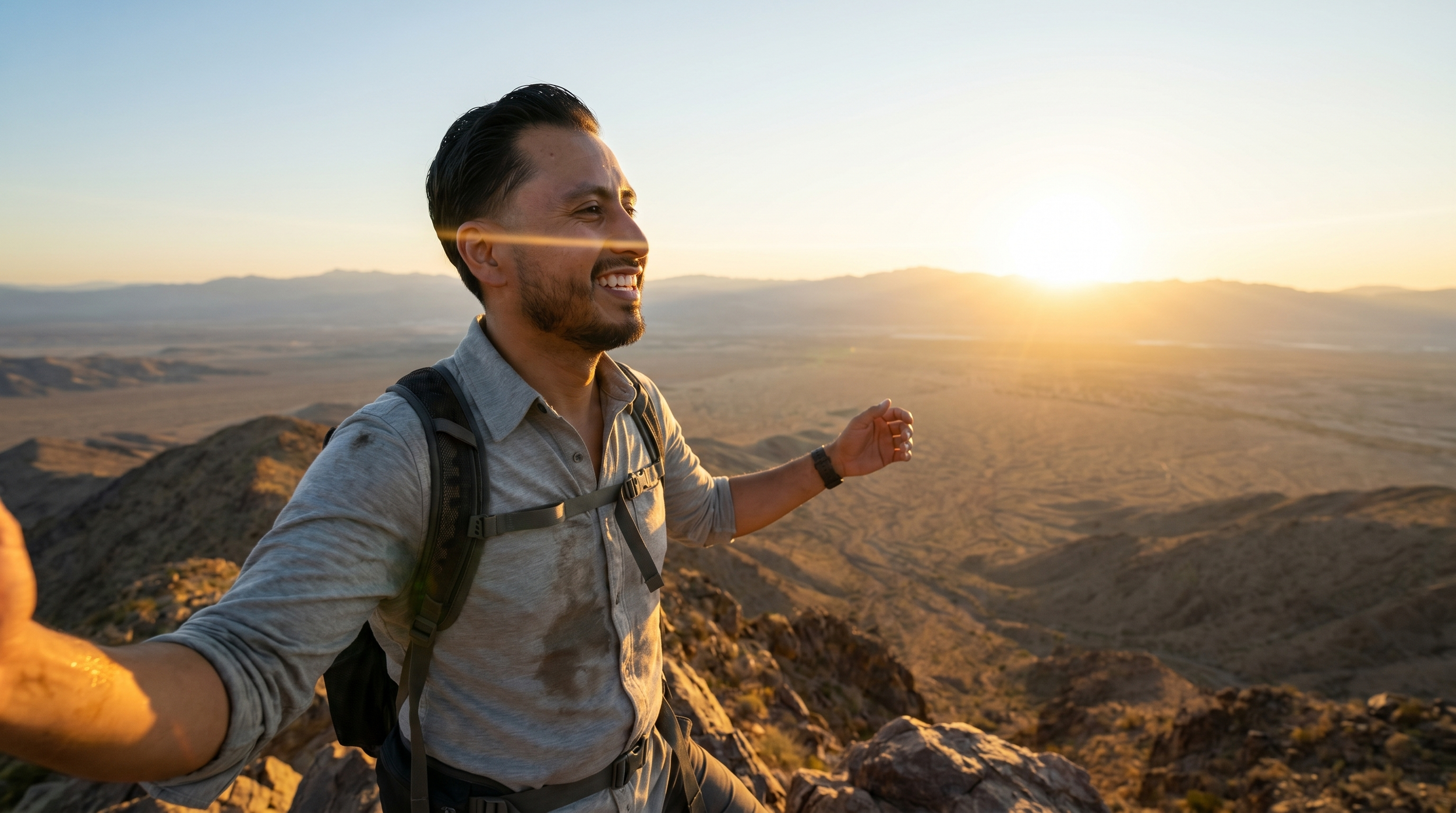 A man hiking on a rocky desert landscape during sunset, smiling and enjoying the view.