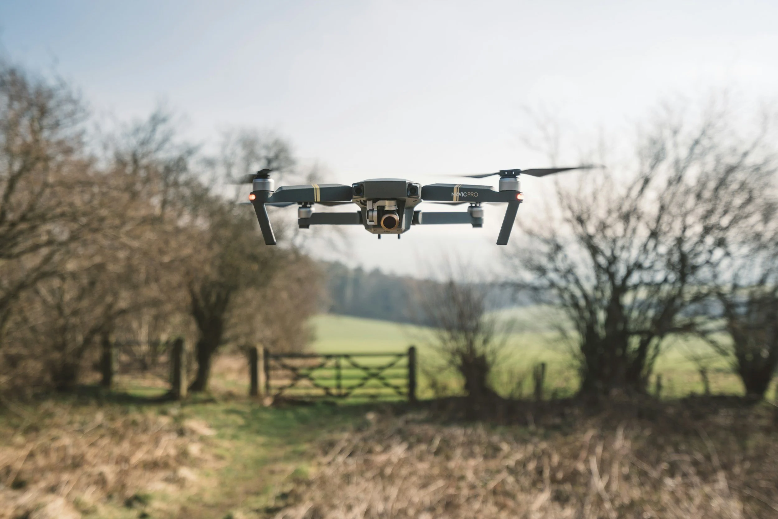 drone hovering over a field near a gate