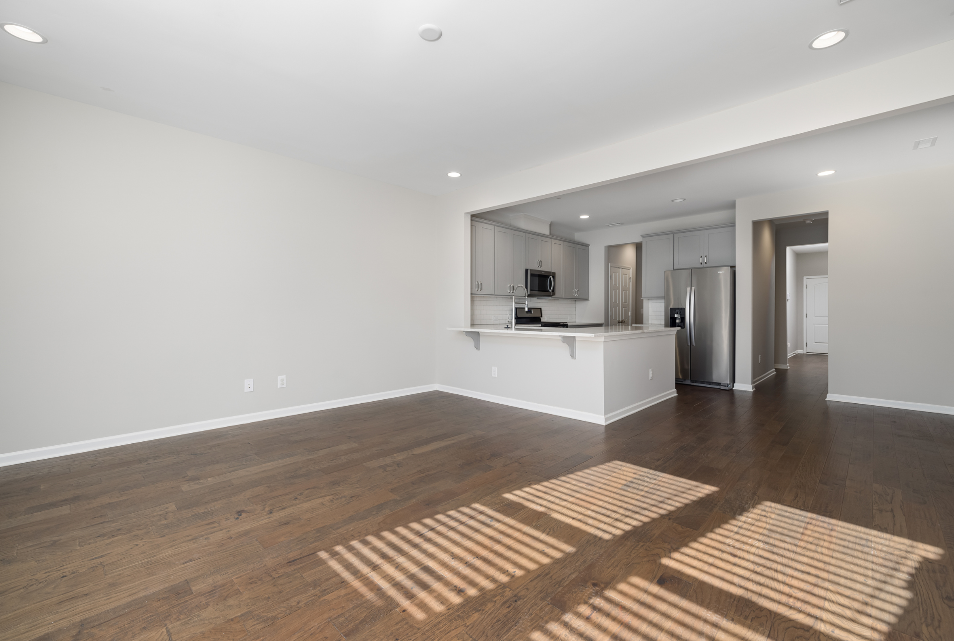 Empty modern apartment with clean hardwood floors and a spotless open kitchen, ready for a move-in or move-out inspection walkthrough.
