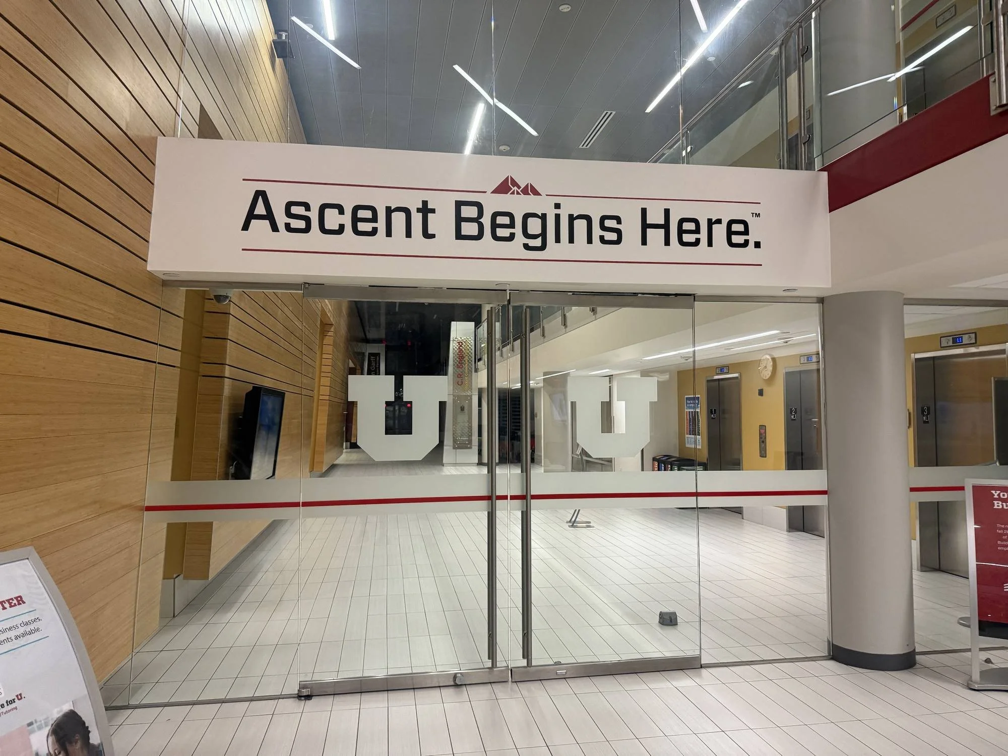 Ascent Begins Here slogan printed above the entrance at the Eccles School of Business, University of Utah