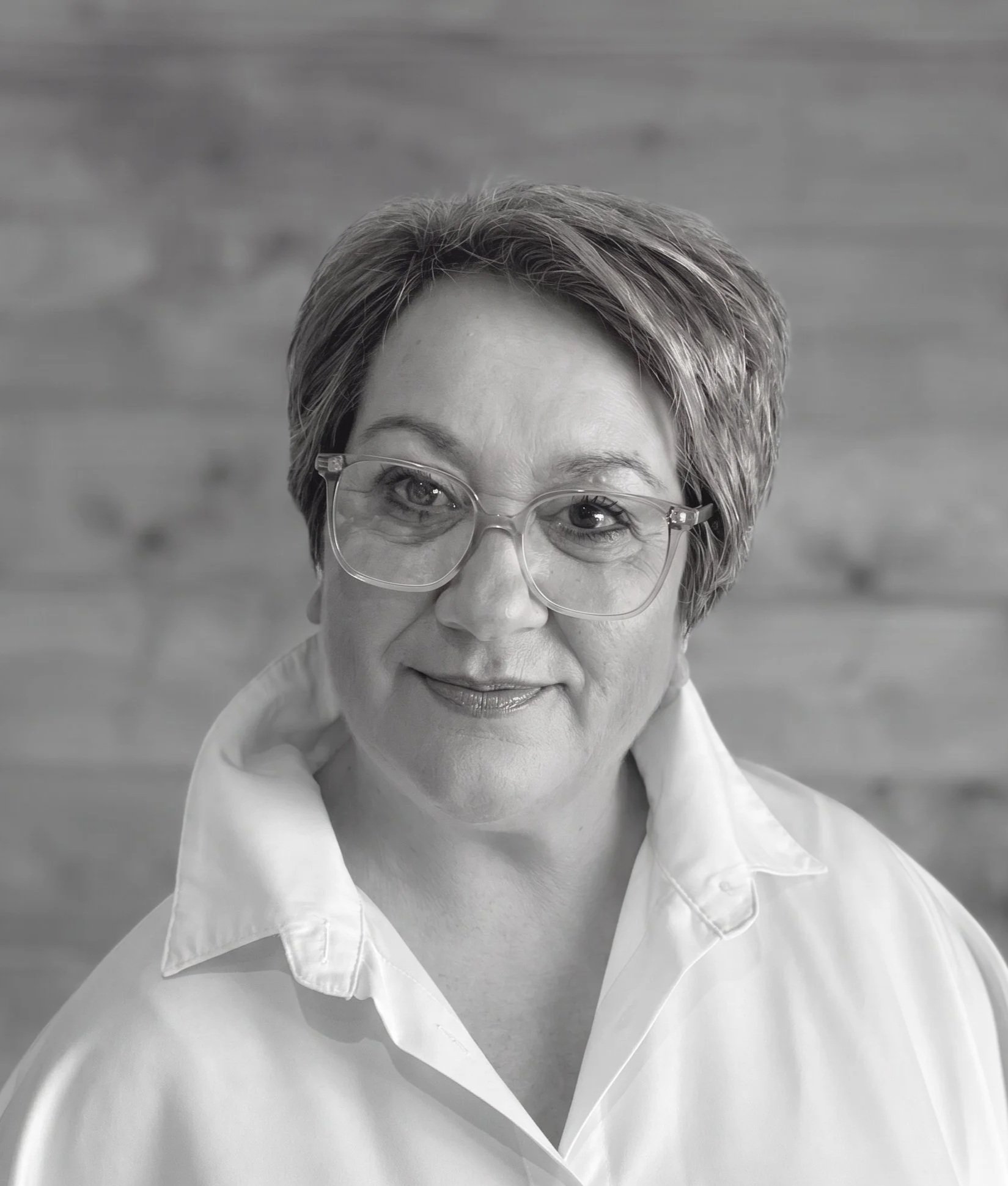 Black and white portrait of an older woman with short hair wearing glasses and a white collared shirt.