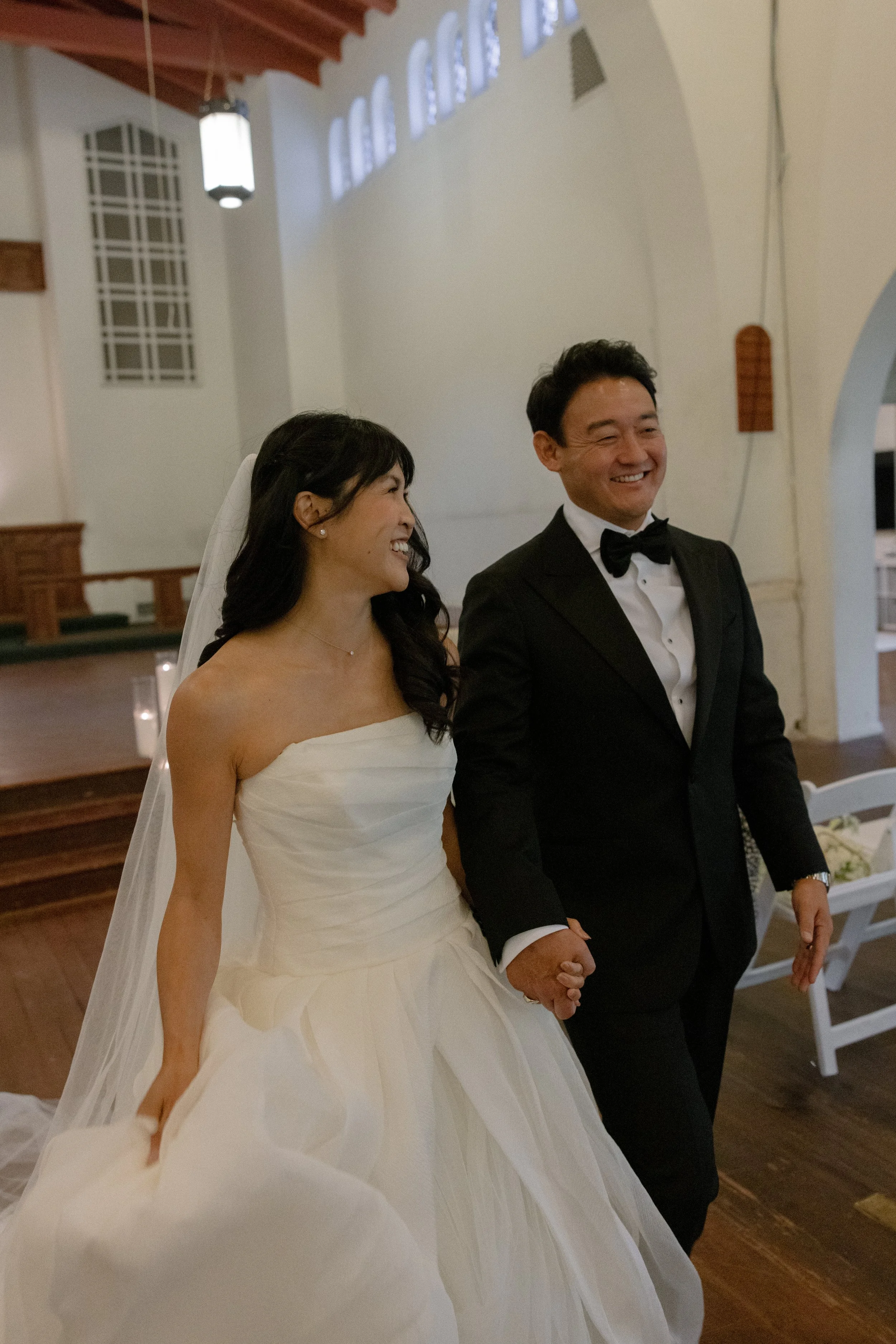 A smiling bride and groom holding hands during a wedding ceremony in a church