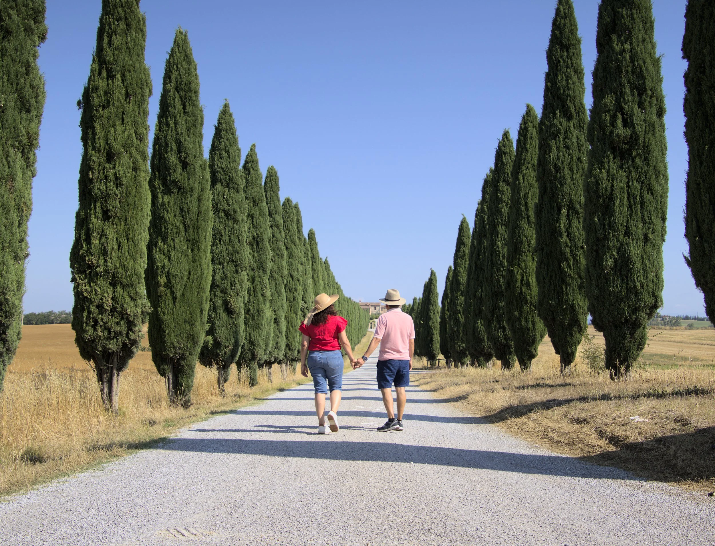 A couple walking by some trees, looking relaxed and unposed