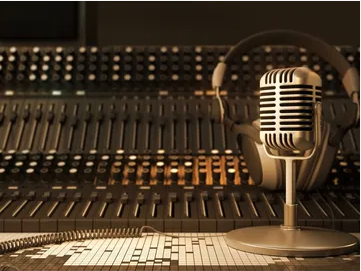 Music studio mixing console with audio equipment, microphone, and headphones.