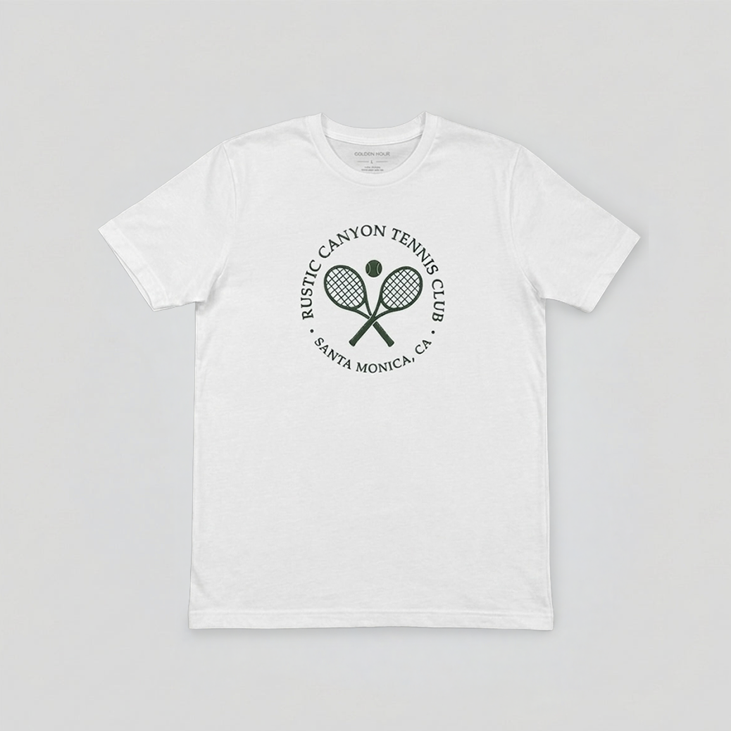 White t-shirt with a green Tennis Club logo featuring two crossed tennis rackets and a tennis ball, with the text 'Rustic Canyon Tennis Club Santa Monica, CA' encircling the logo.