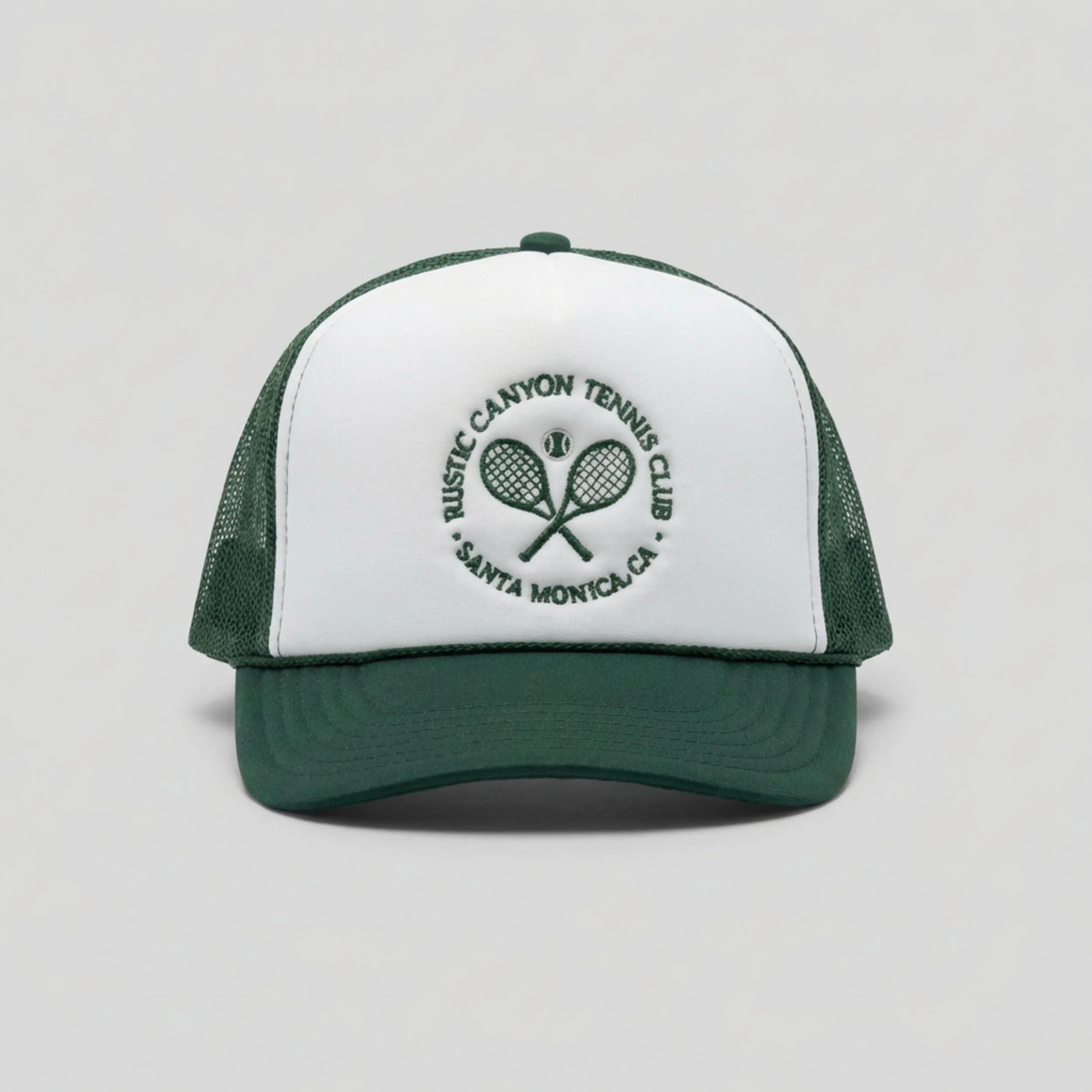 Close-up of a white and green trucker baseball cap with the logo of the Pacific Canyon Tennis Club on the front