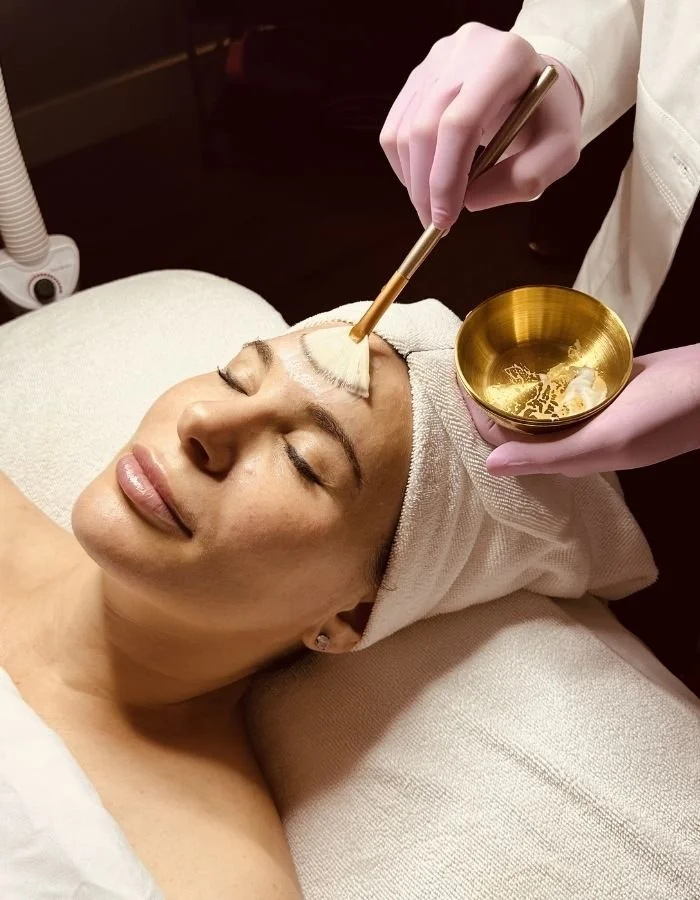 Chemical peels solution being applied to a female client's forehead during a customized facial at Avila Skin Studio in McKinney