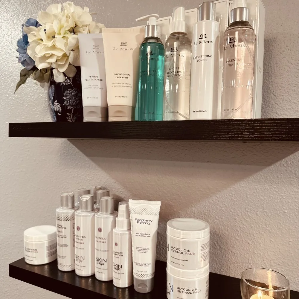 Two dark wooden shelves mounted on a wall display various skincare professional skin care products available for sale at Avila Skin Studio.