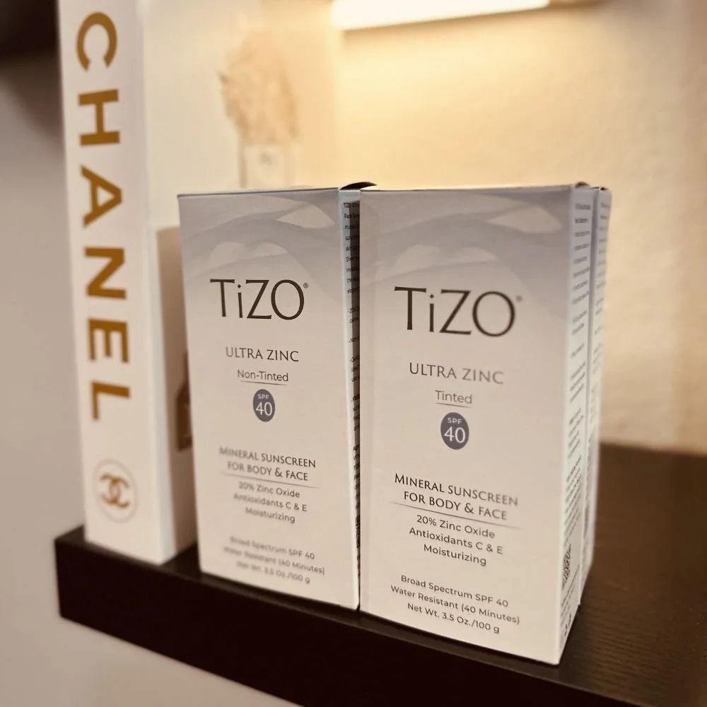 Two boxes of Tizo Ultra Zinc mineral sunscreen, one non-tinted and one tinted, both with SPF 40, placed on a dark surface.