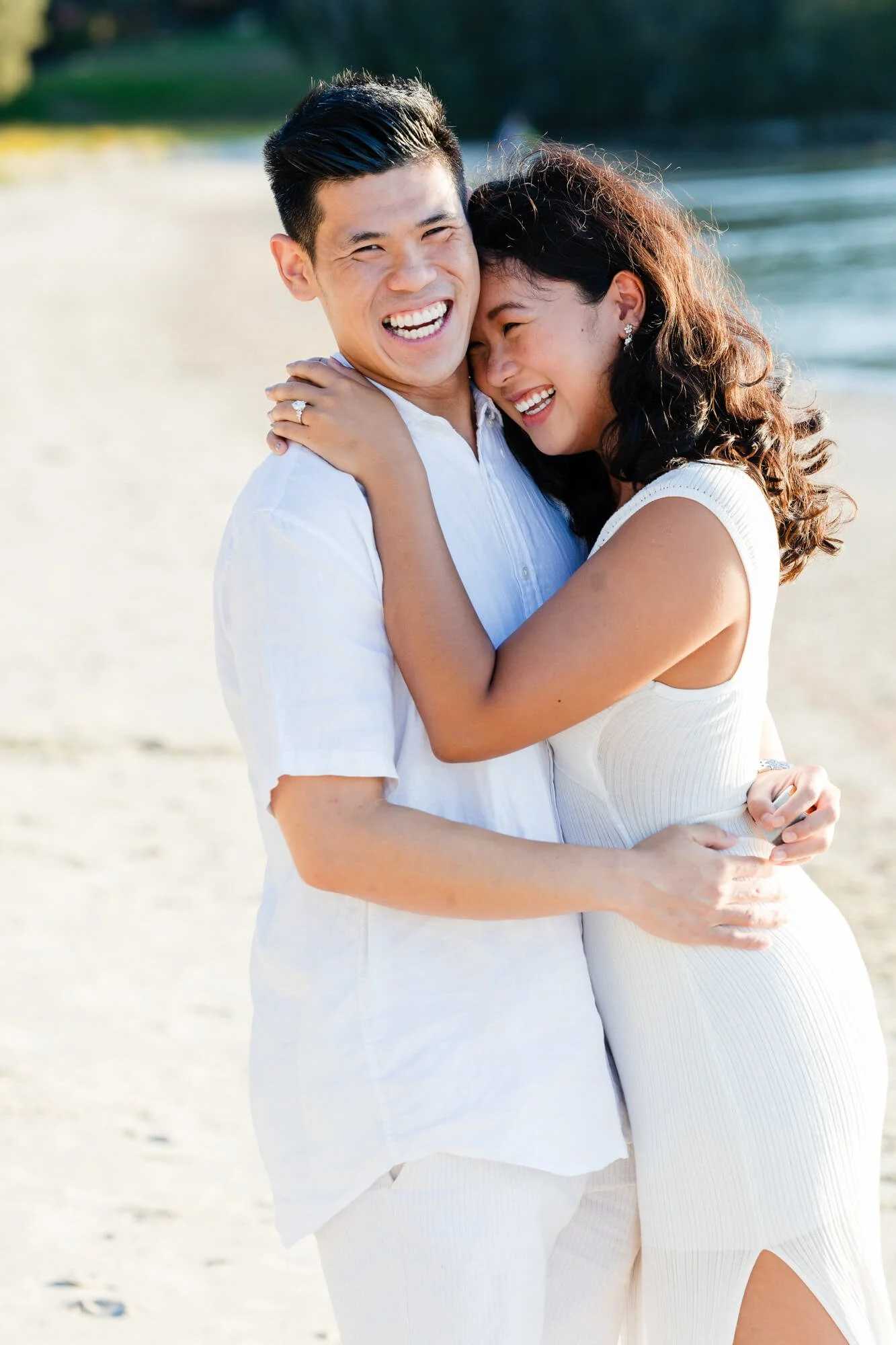 Newly engaged couple laughing and hugging on a sandy beach, Soldiers Point, Port Stephens.