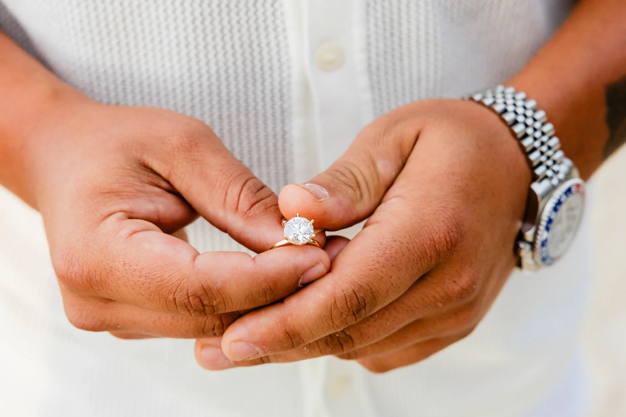 Close-up of a man's hands holding a diamond engagement ring, a steel wristwatch on his wrist, just before the proposal, Dutchmans Beach, Nelson bay, Port Stephens.