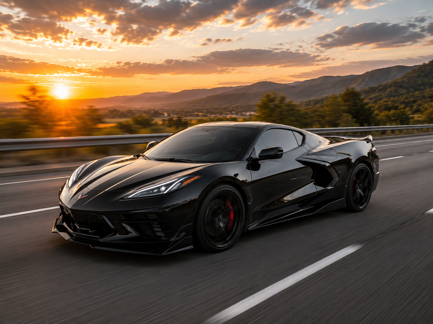 A black sports car driving on a highway during sunset, with mountains and a partly cloudy sky in the background.