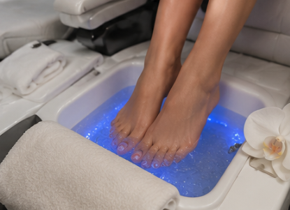 Person's feet soaking in a foot spa with blue LED lights