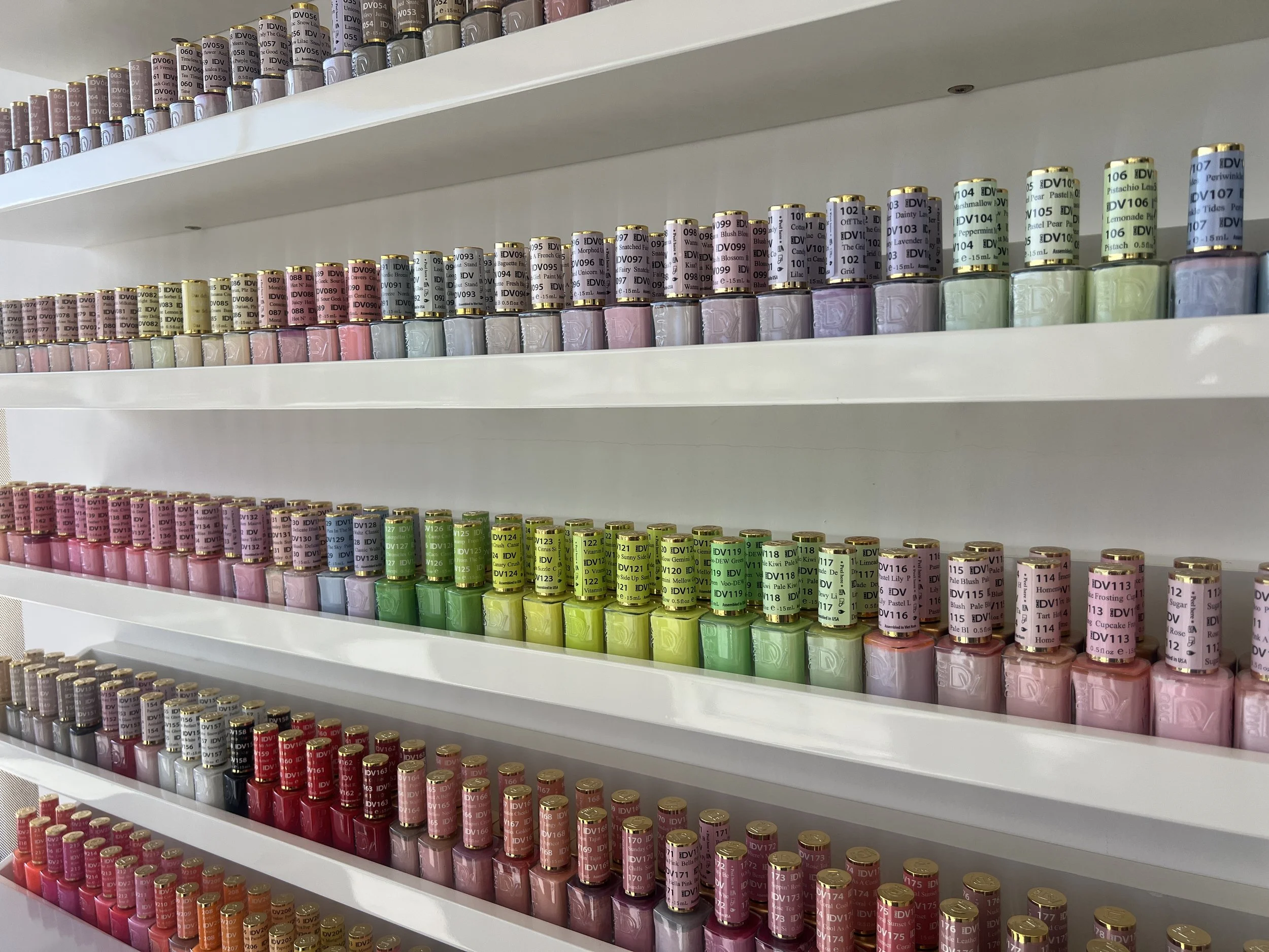 Estanterías llenas de frascos de esmalte de uñas en diferentes colores y tonos.