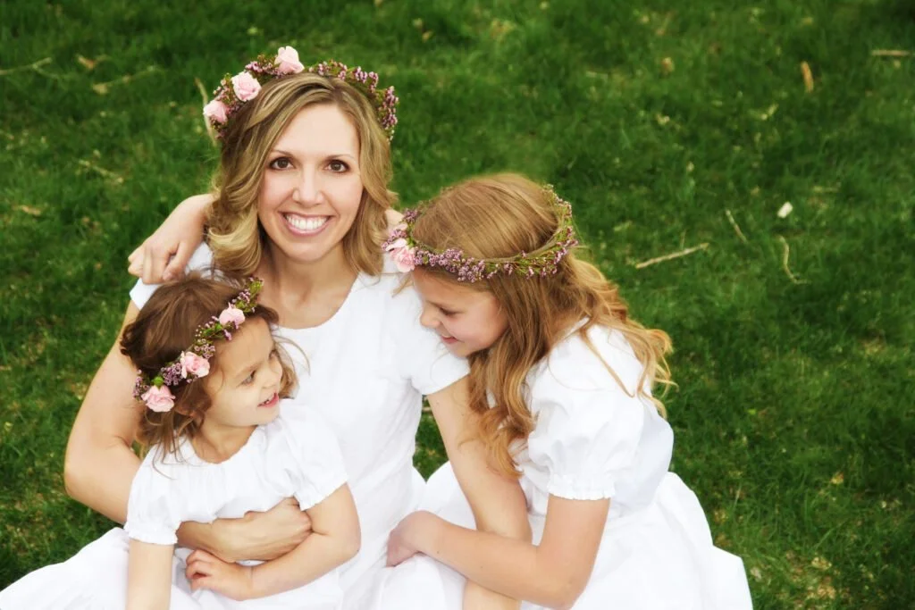 Woman sitting with two young girls in white dresses