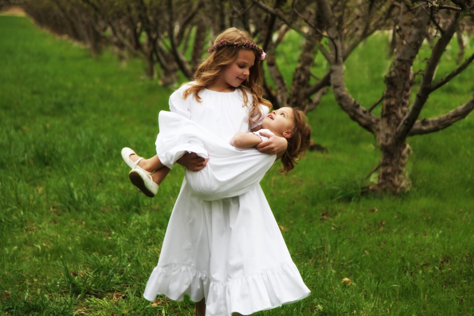 young girl carrying a smaller girl in her arms