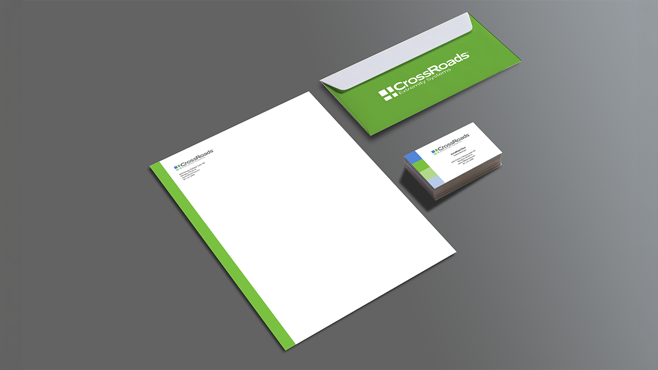 Business stationery set including letterhead, business cards, and an envelope with Crossroads branding and logo on a gray surface.