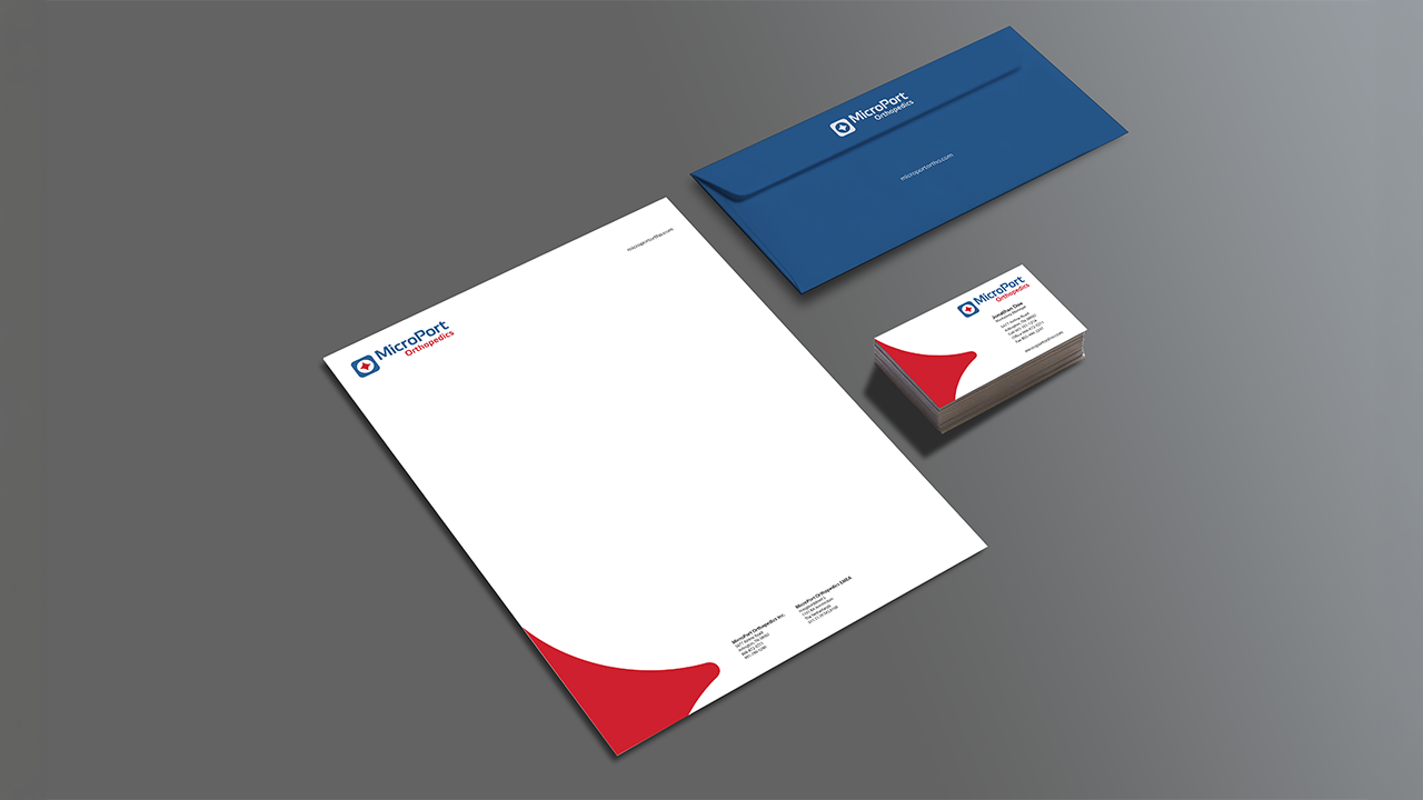 Corporate stationery set for MicroPort Orthopedics, including a letterhead, business card, and a blue envelope on a gray background.