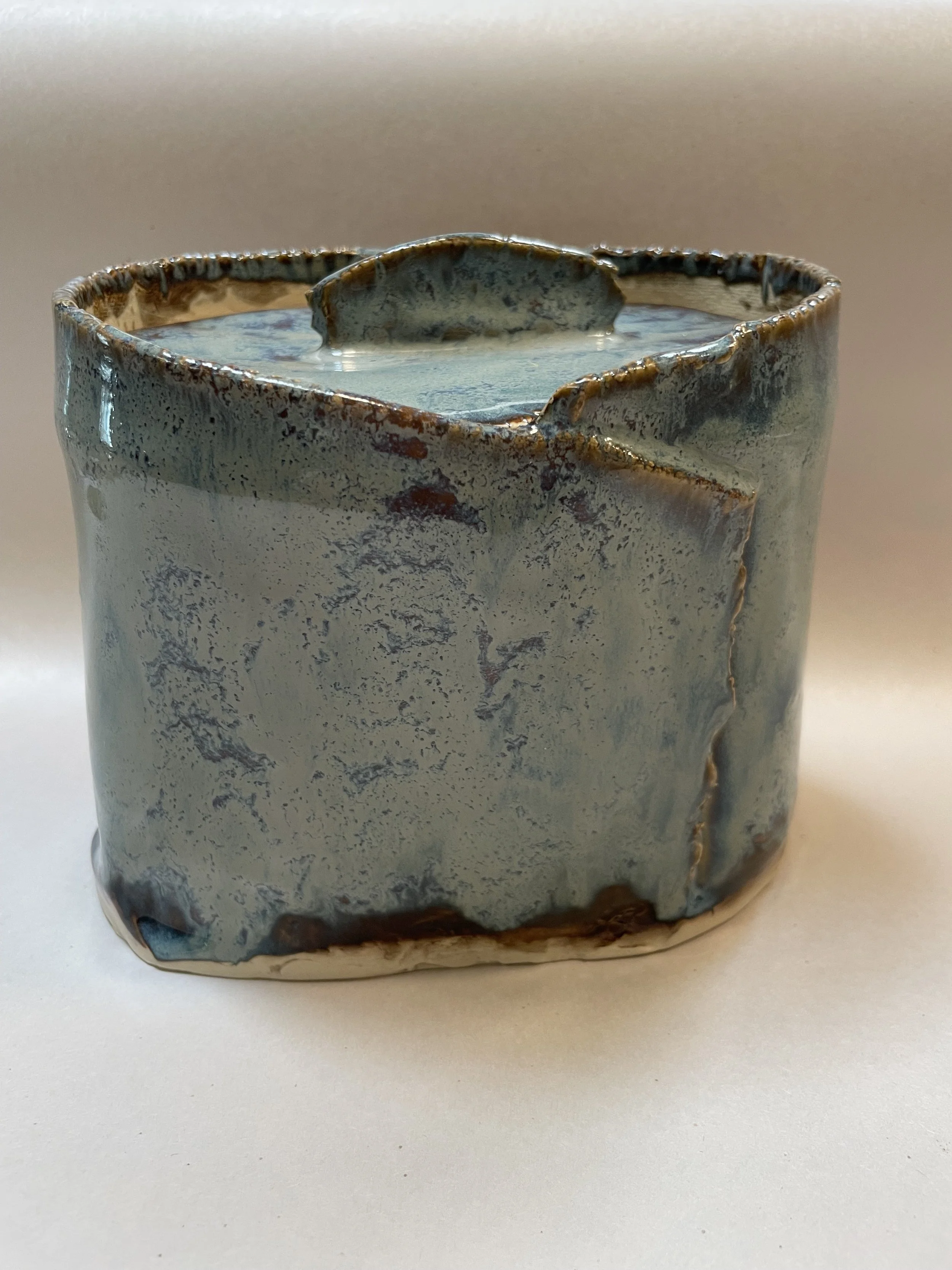 A ceramic mug with a textured, marbled glaze finish, filled with liquid, placed on a plain surface.