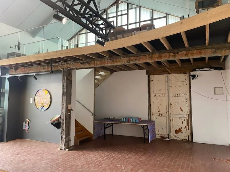 Interior of the Bodalla Arts Factory showcasing the handcrafted timber beams, exposed framework, and natural light filtering through the loft, highlighting the building’s detailed craftsmanship and restored industrial charm