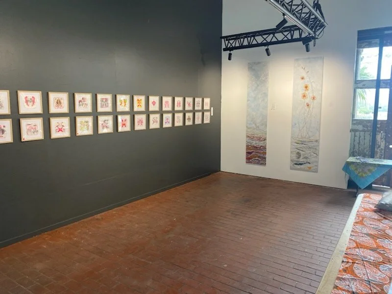 Gallery wall inside the Bodalla Arts Factory displaying a series of framed artworks and large vertical canvases, showcasing the versatile wall space available for exhibitions and installations