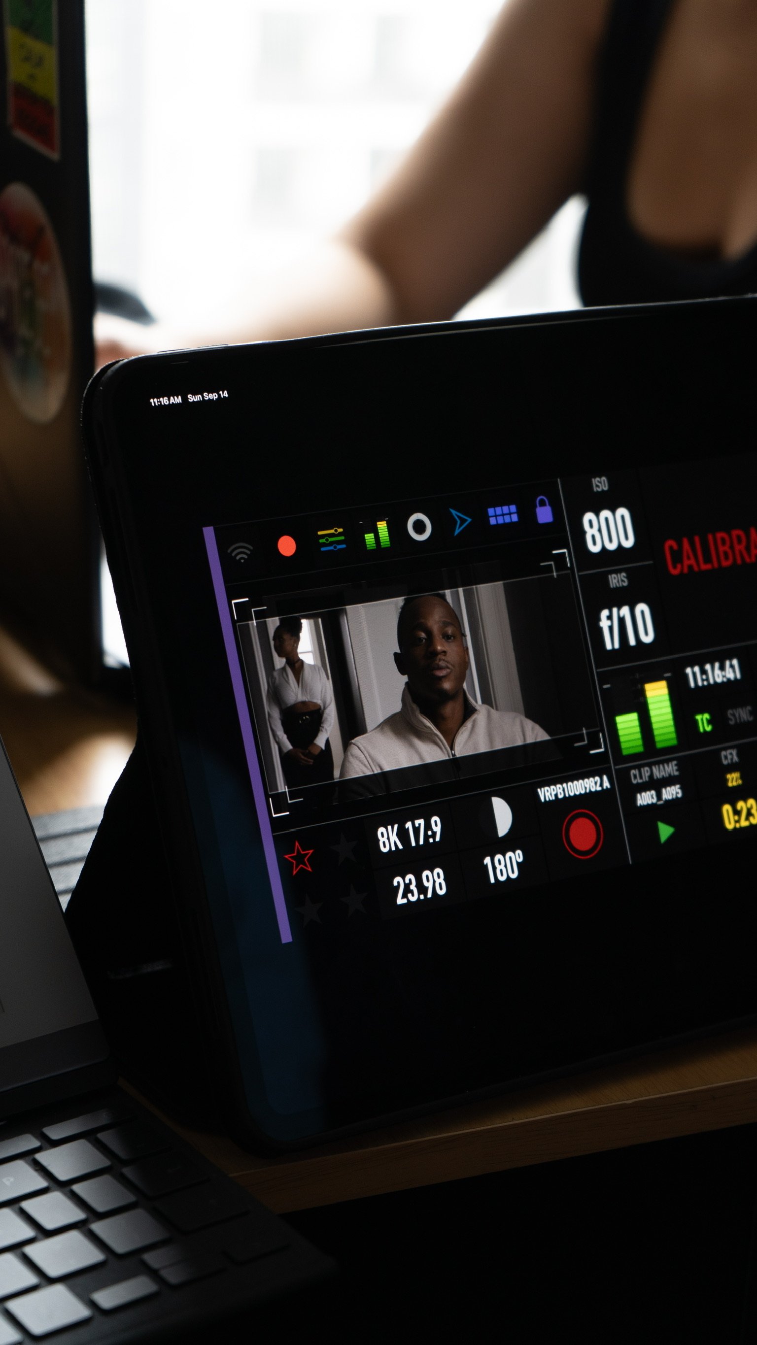 Smartphone with video recording app, showing a man and woman standing indoors, with various camera settings and controls visible on the screen.