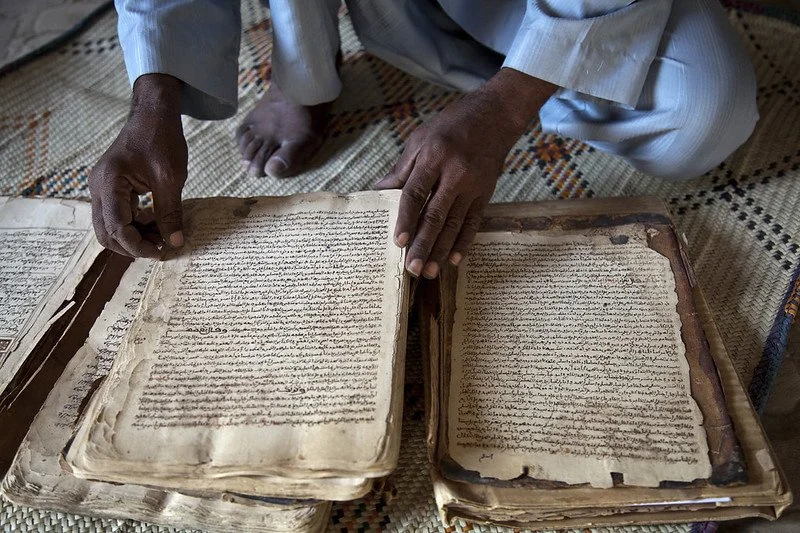 A picture of a man handling the pages of an ancient manuscript