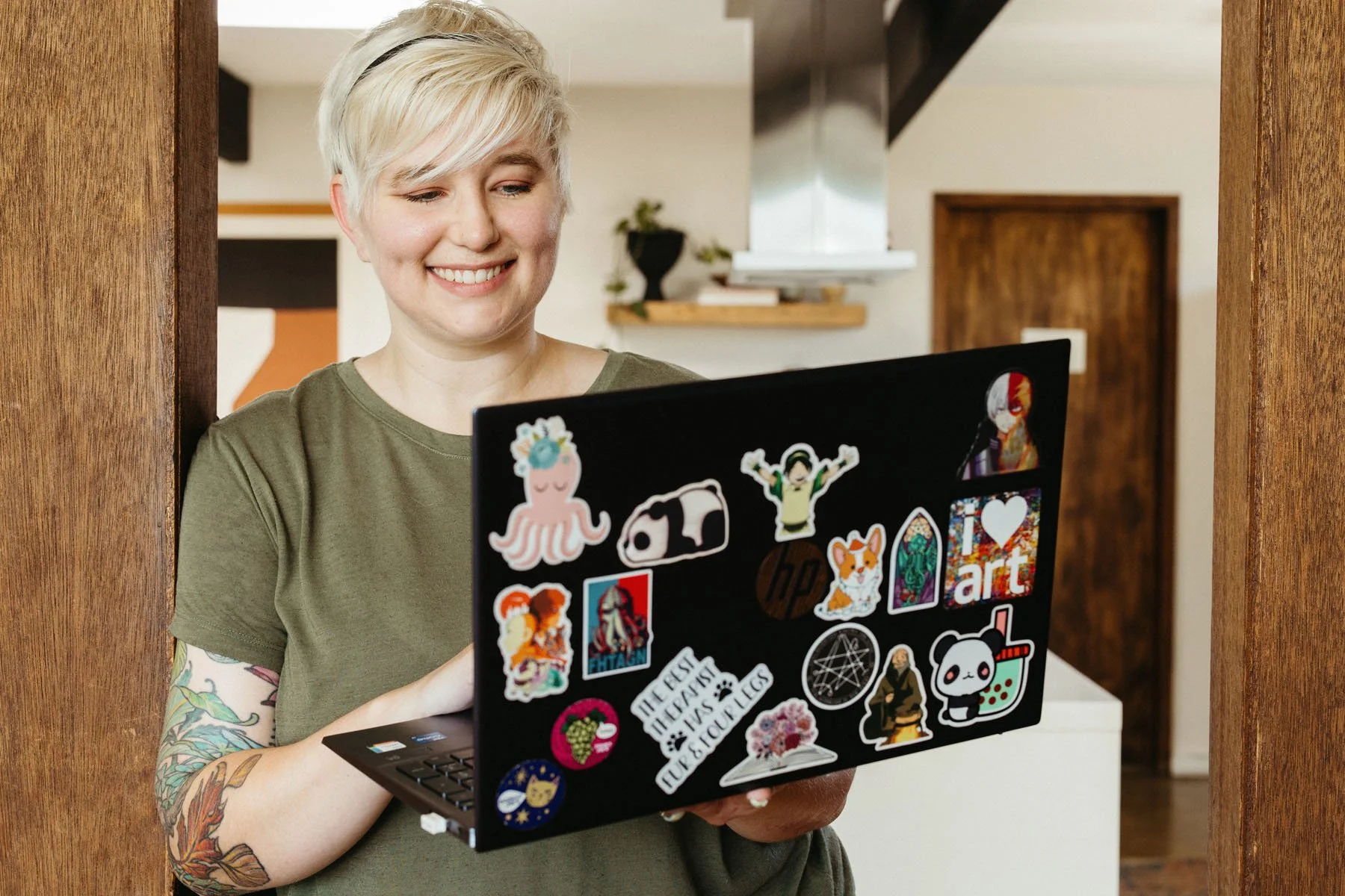 Lauren Abbott smiling as she looks at her laptop, which is covered with colorful stickers.