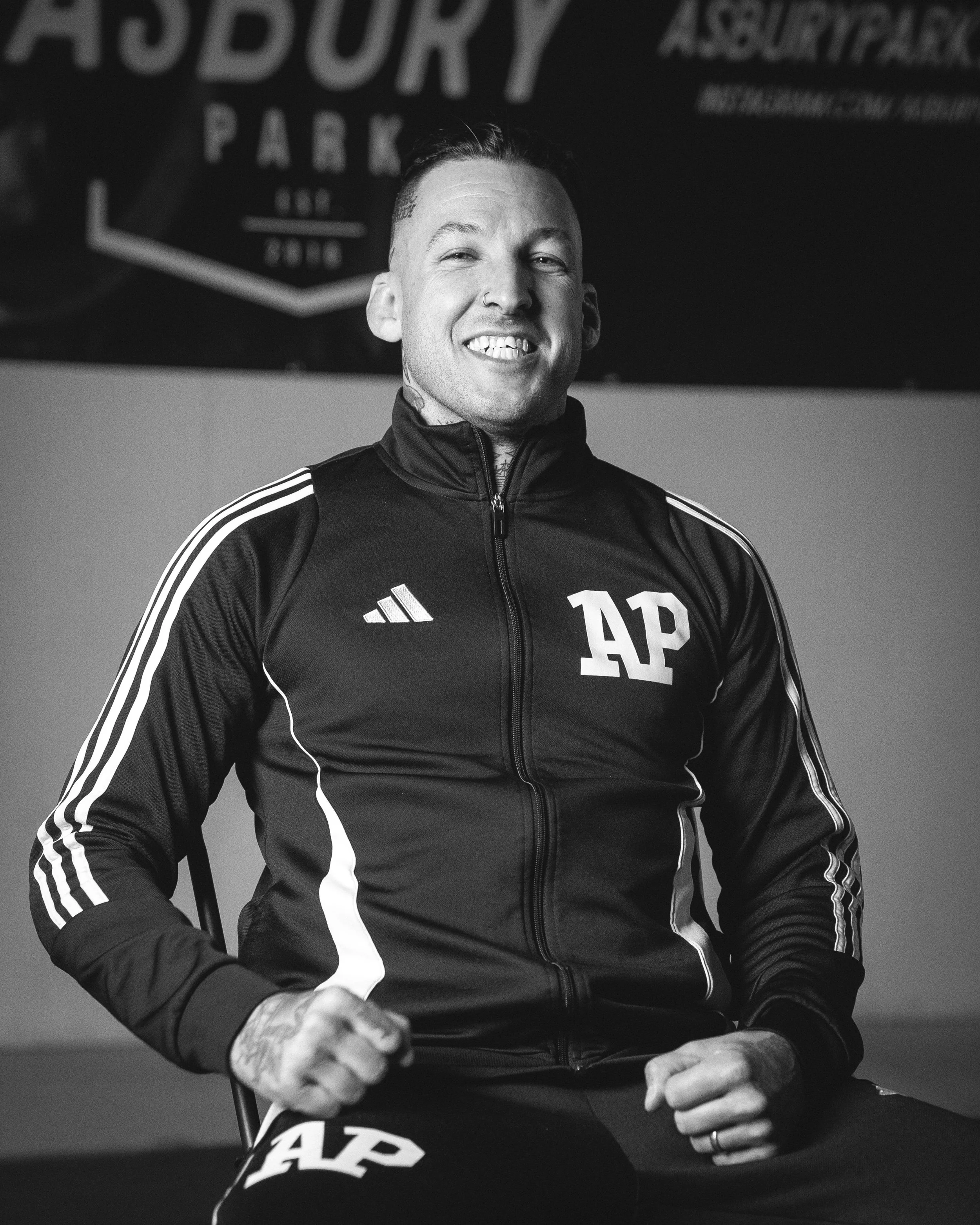 Asbury Park Jiu Jitsu head coach smiling in Adidas training jacket outside the academy.