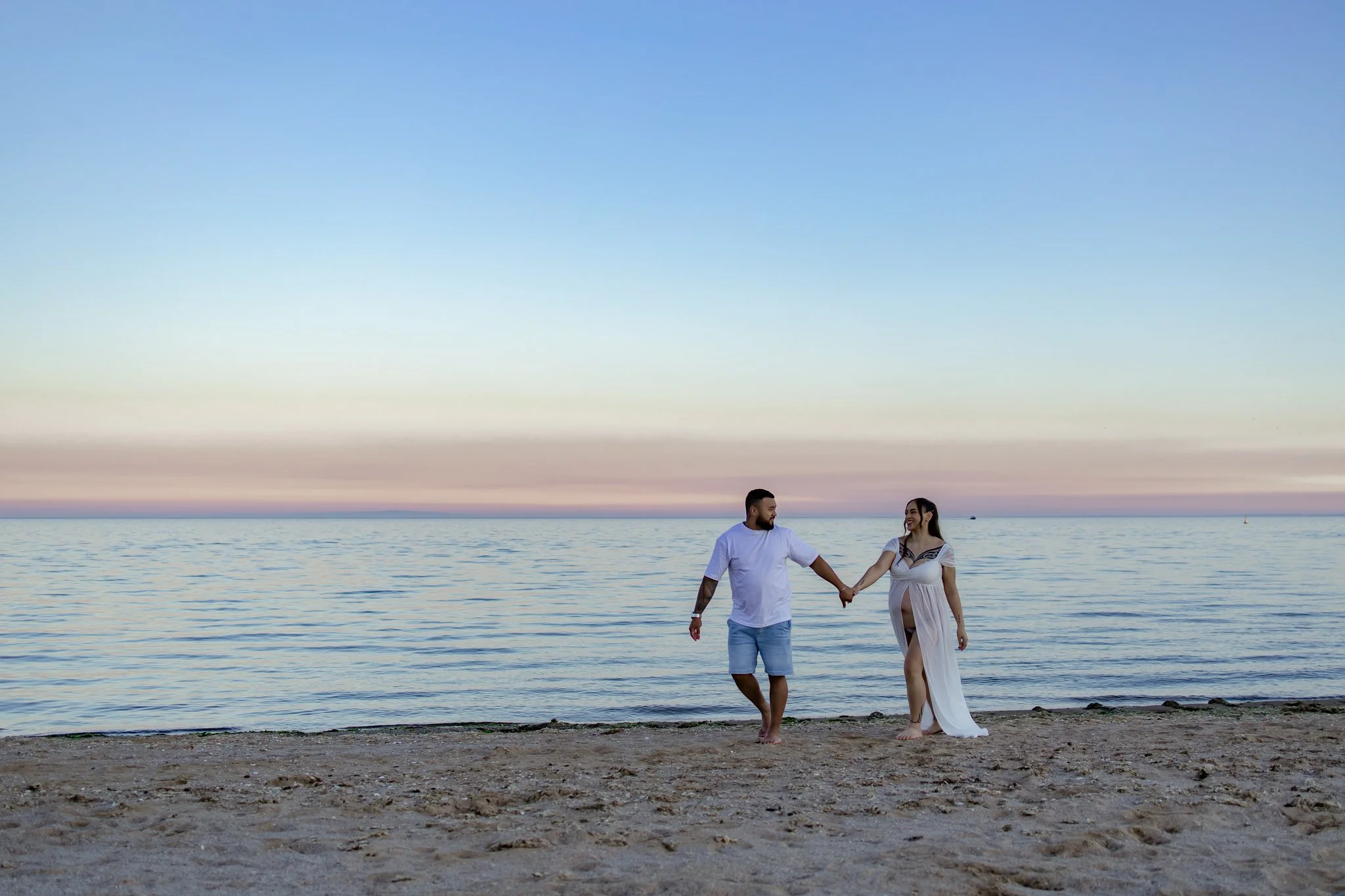 Maternity photography, couple walking along the beach in Werribee at their Maternity photography session with Bunch Photography