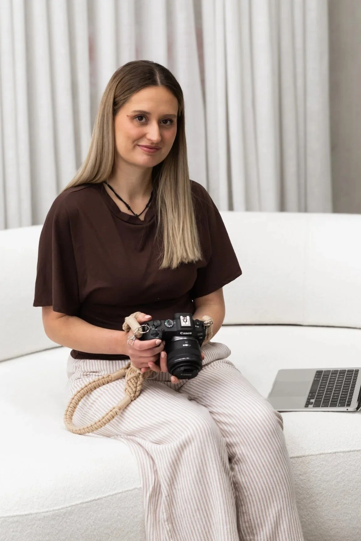 Samara Melbourne newborn photographer holding camera and sitting on a couch