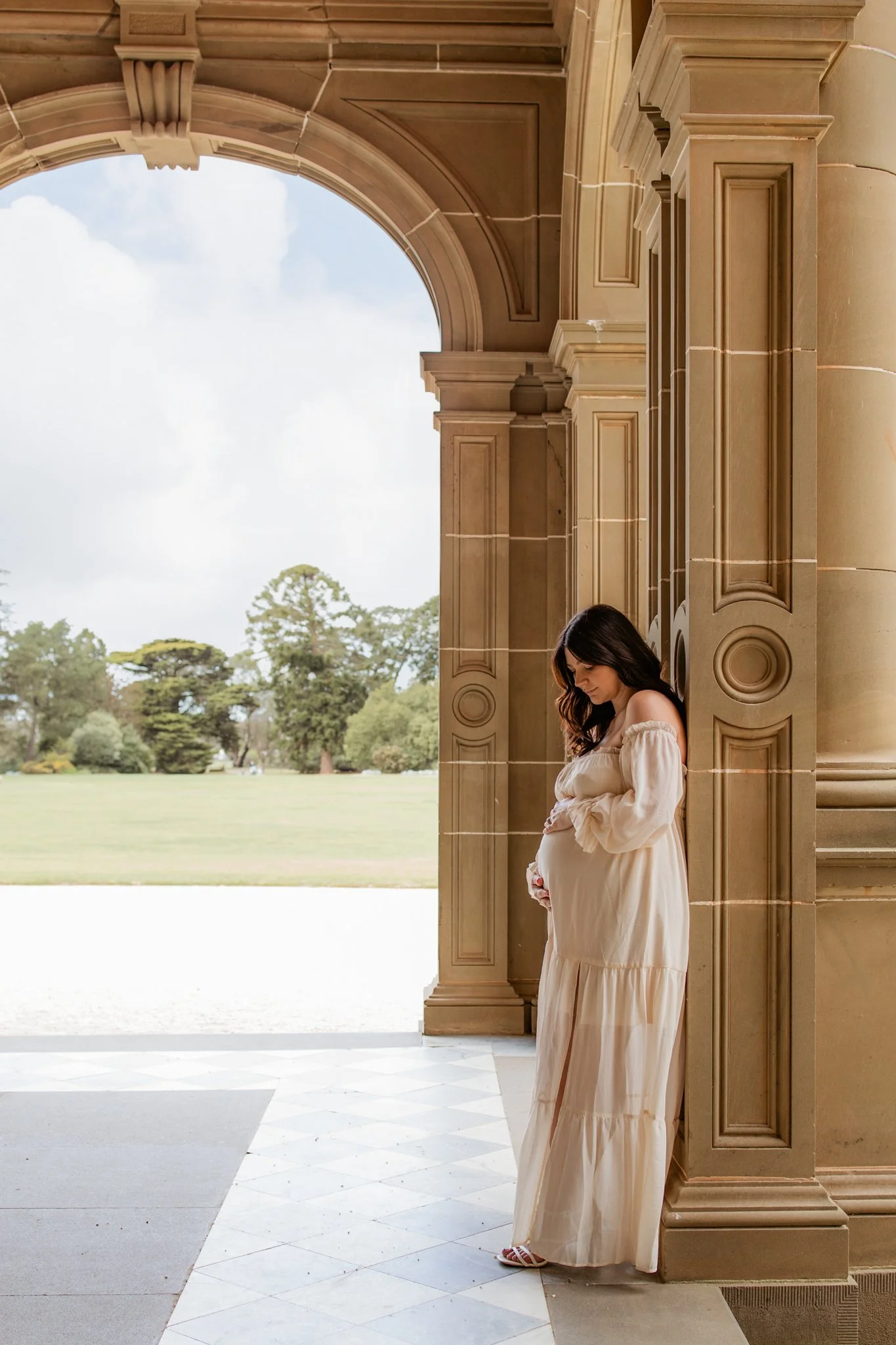 Mum to be at her maternity photography session looking down at her growing bump at Werribee Mansion
