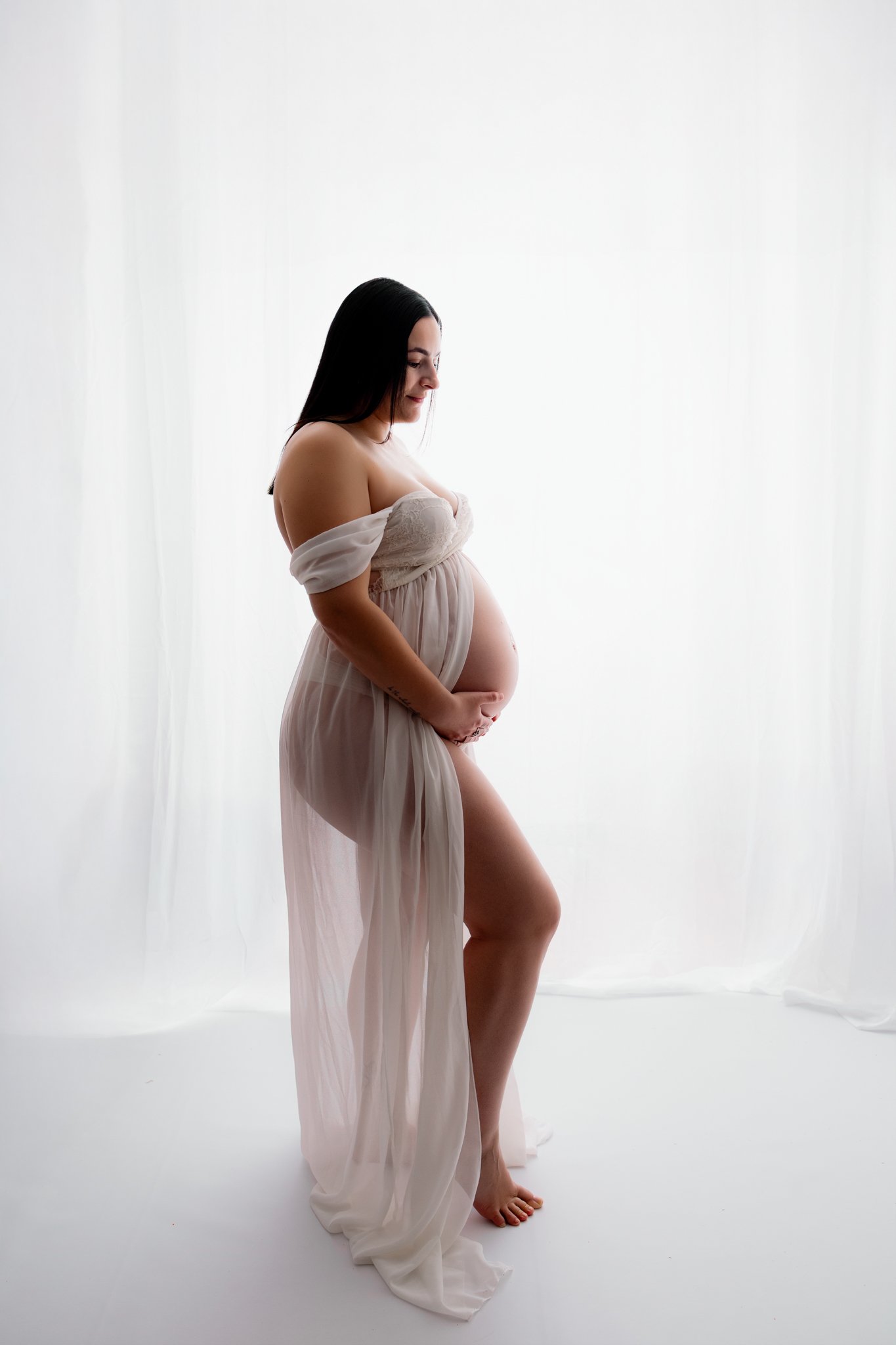 Mum cradling her pregnant belly at a studio maternity photography session in Melton West