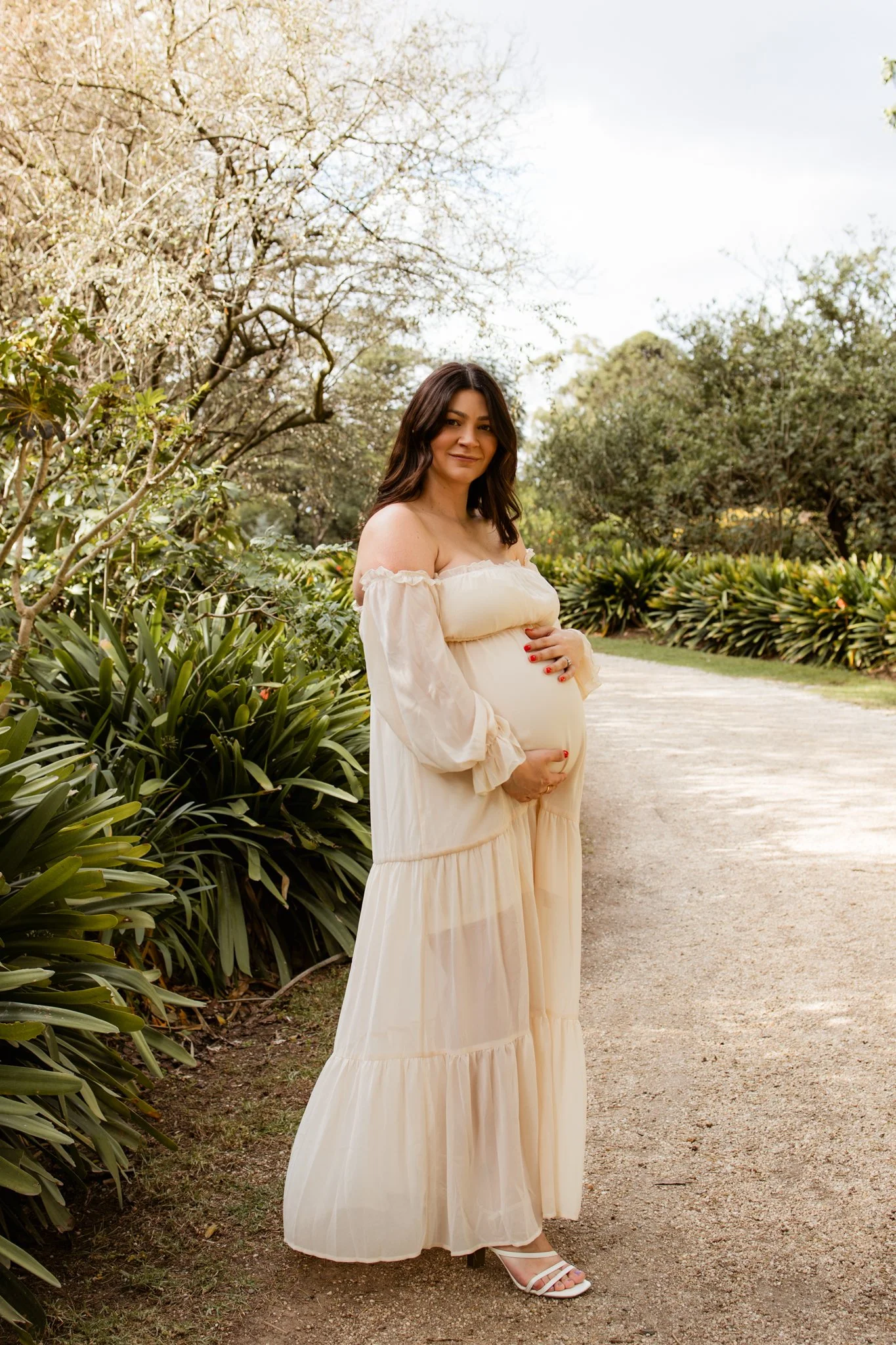 Pregnant mother holding her belly in a maternity dress at her maternity photoshoot at Werribee Mansion with Bunch Photography
