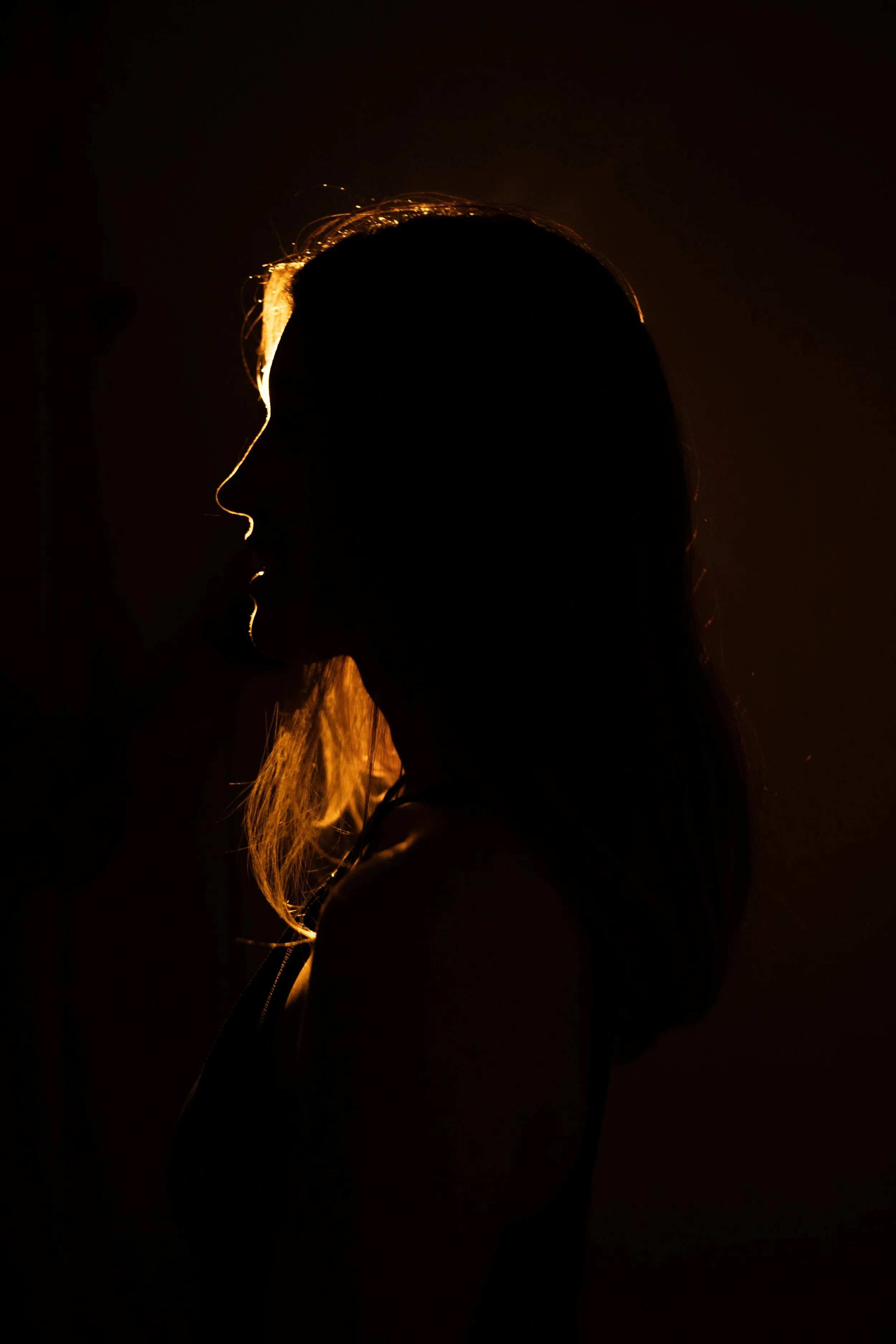 Silhouette of a person with glowing hair traced by light, standing against a dark background.
