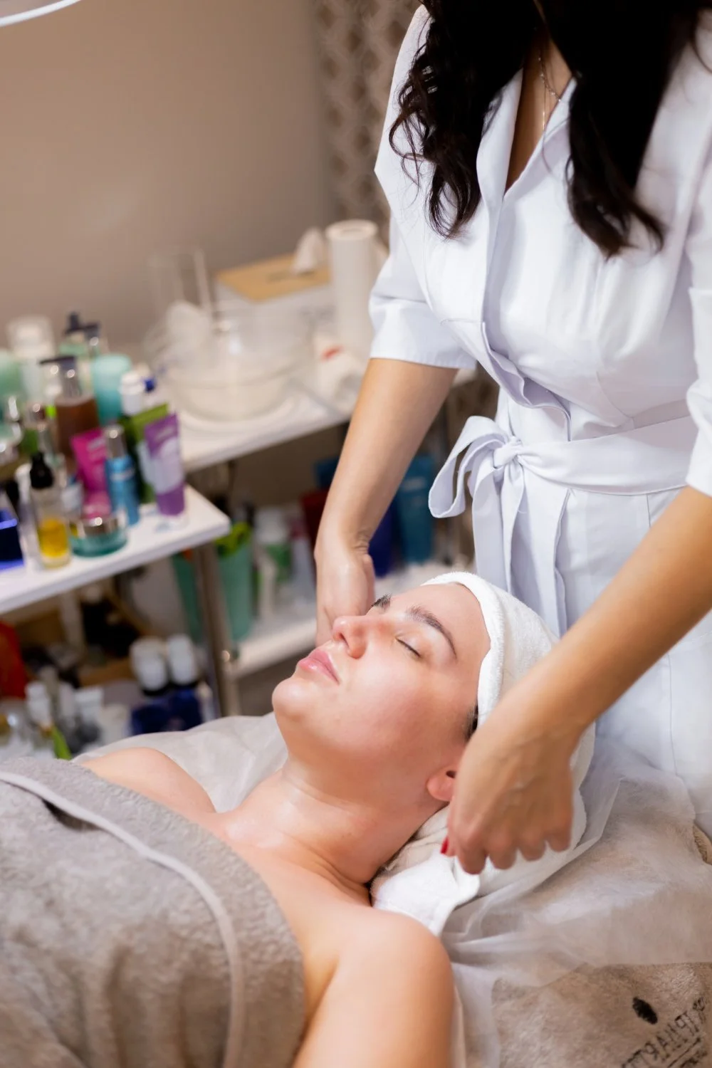 A woman receiving a facial treatment from a professional in a spa or skincare clinic. | Modern roots healthcare