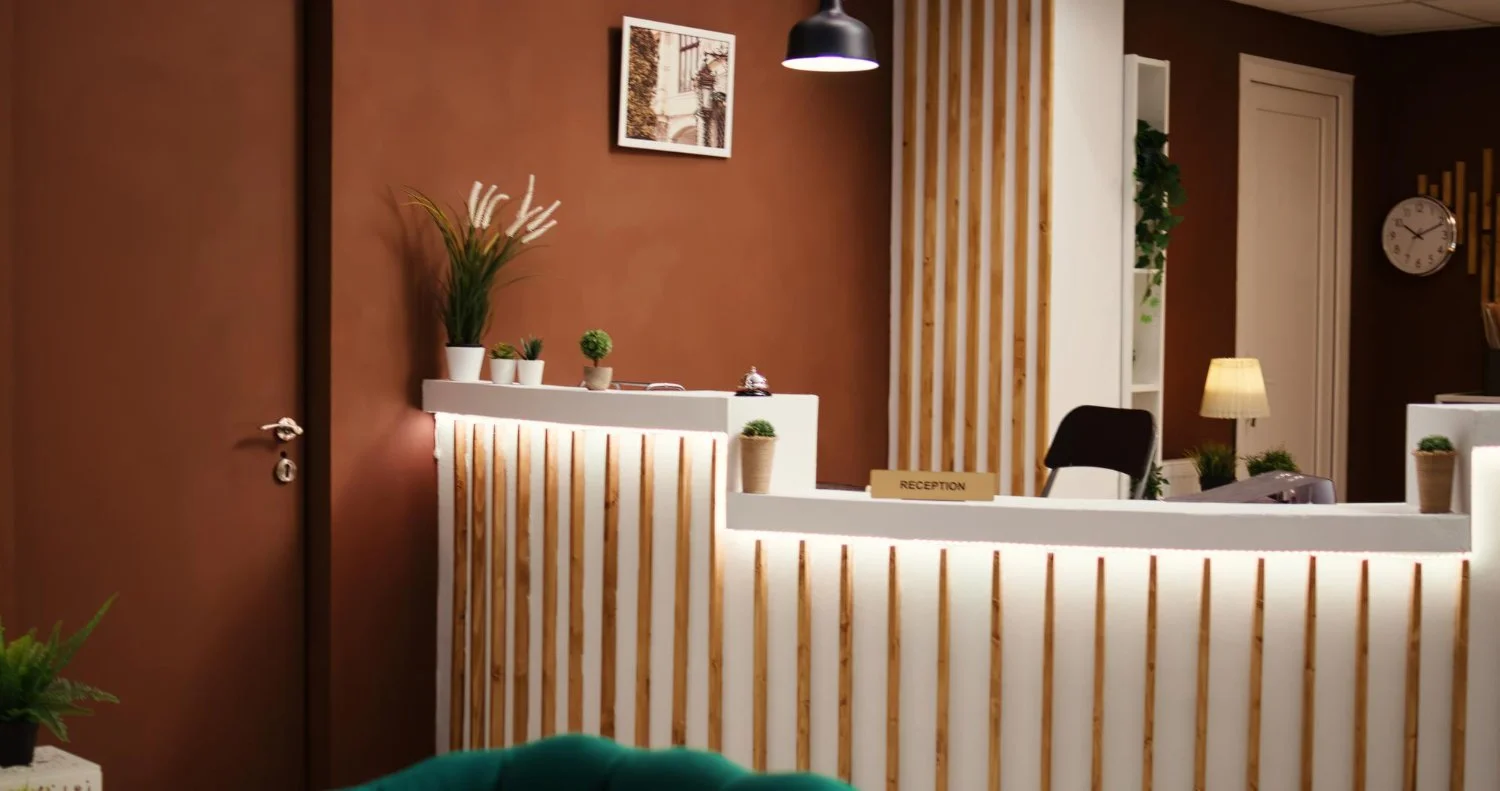 Modern roots healthcare reception desk with plants, artwork, and warm lighting in a modern interior.