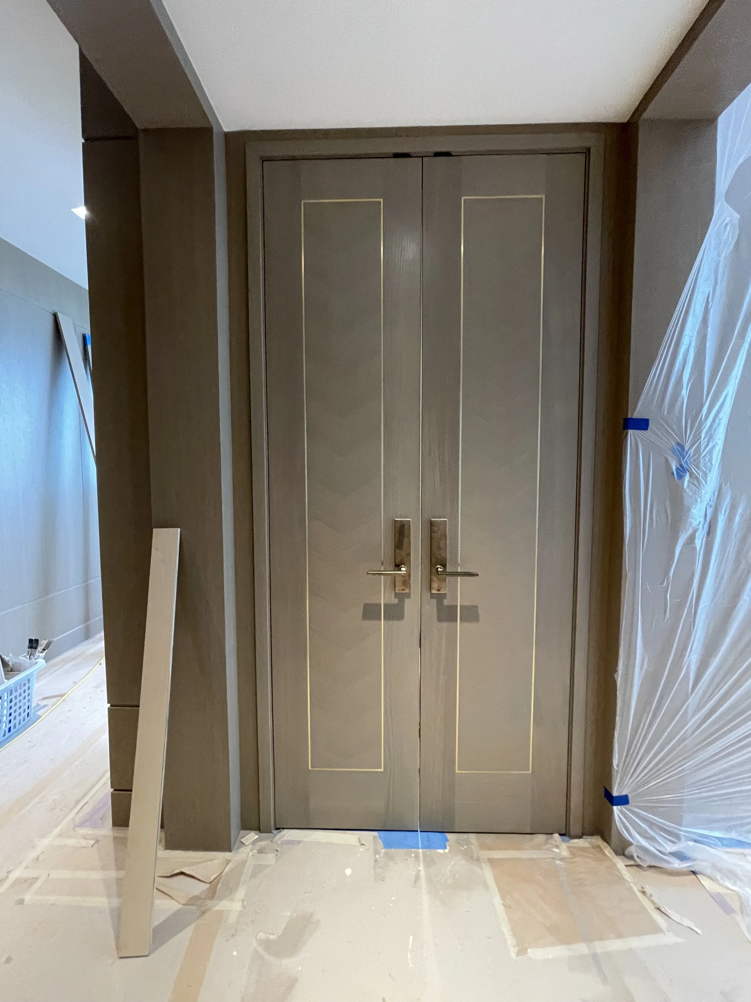 Interior of a room with an empty closet and partially covered floor, door frame, and wall sections under construction or renovation.