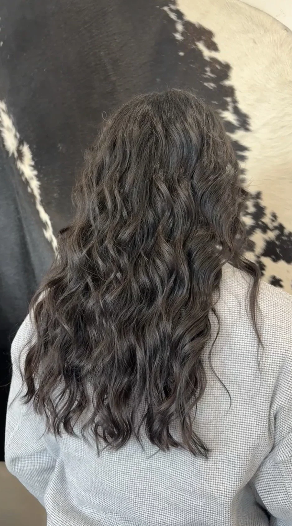 Back view of a person with long, wavy, dark brown hair.