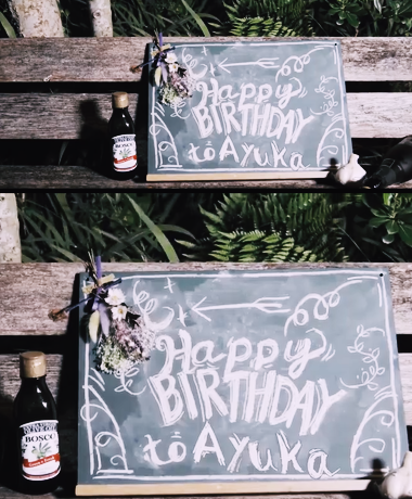 誕生日のお祝いのメッセージと飾りが書かれた黒板とビールボトルが置かれている風景