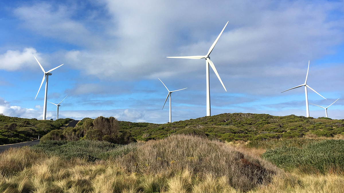 A landscape with wind turbines on a hill, under a partly cloudy sky.